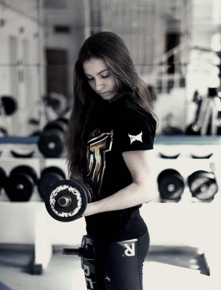 Atleta entrenando con mancuernas en la sala de un centro deportivo.